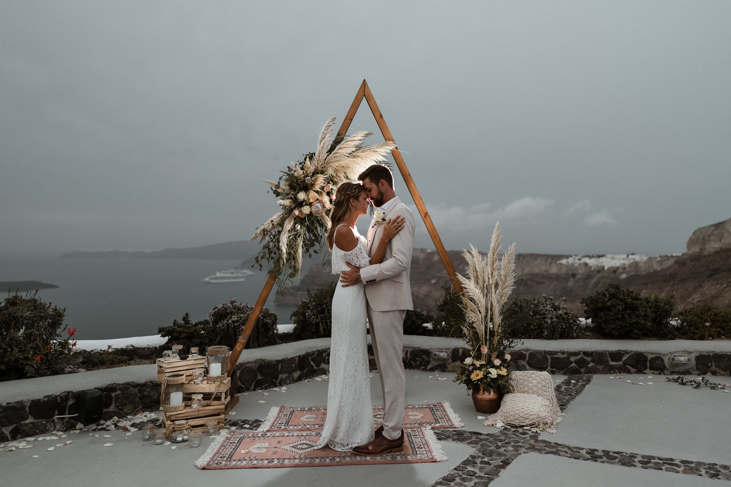 A couple standing in front of a wedding arch full of flowers at Venetsanos winery.