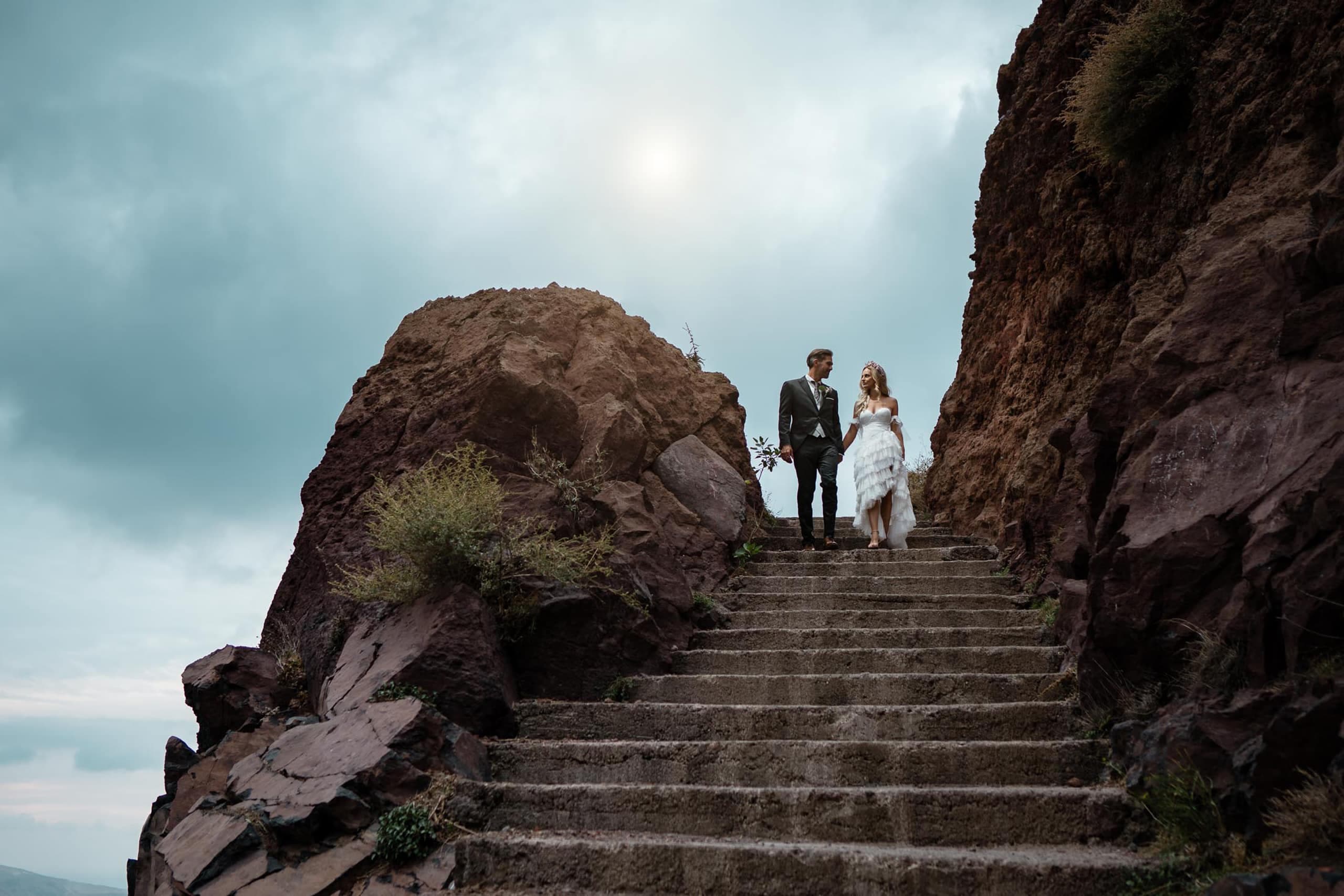 Couple walking down the stairs at Skaros rock in Santorini Greece.