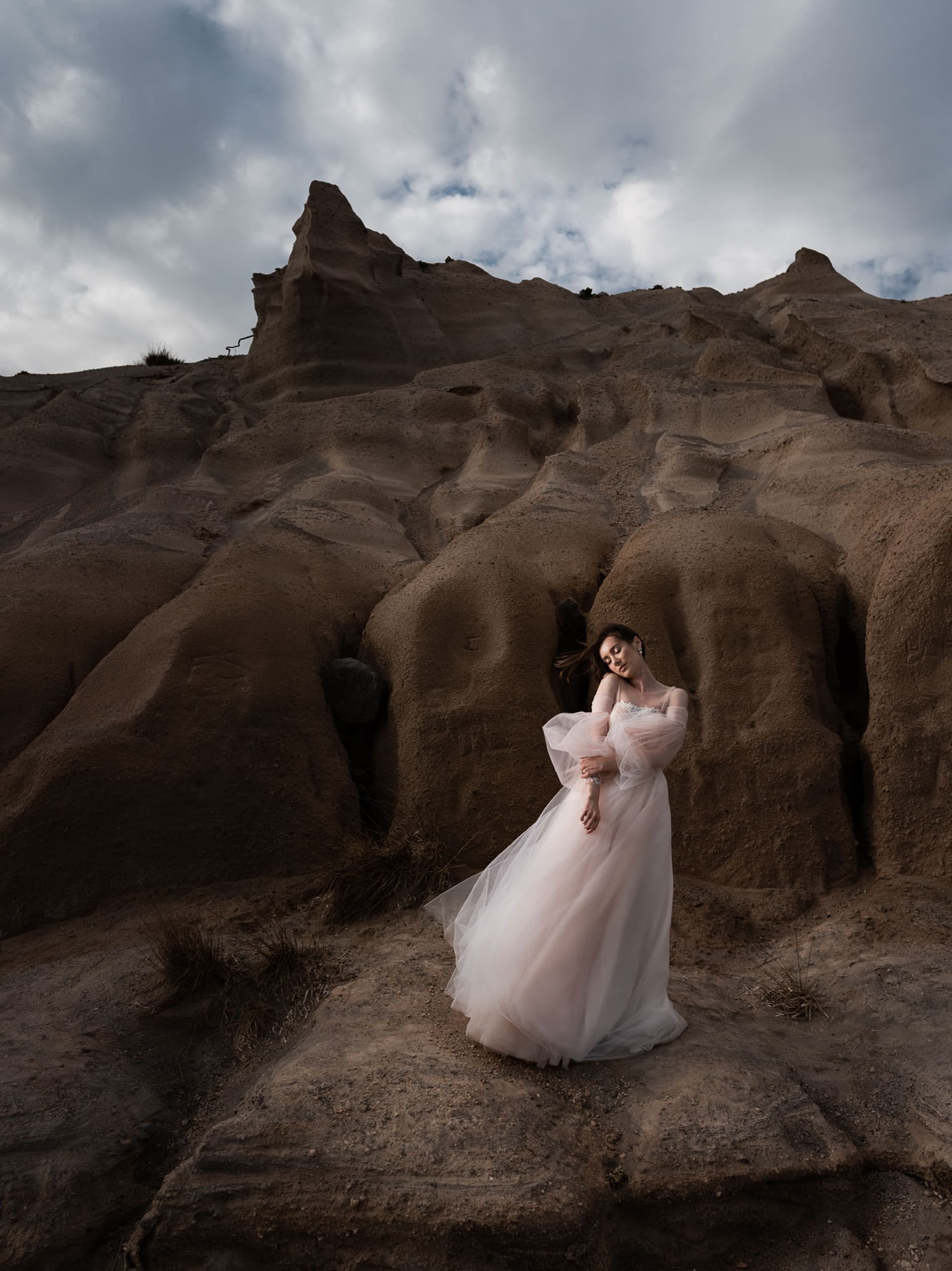 A bride on her wedding dress, posing at iconic black beach. A dramatic bridal portrain in Santorini, Greece.