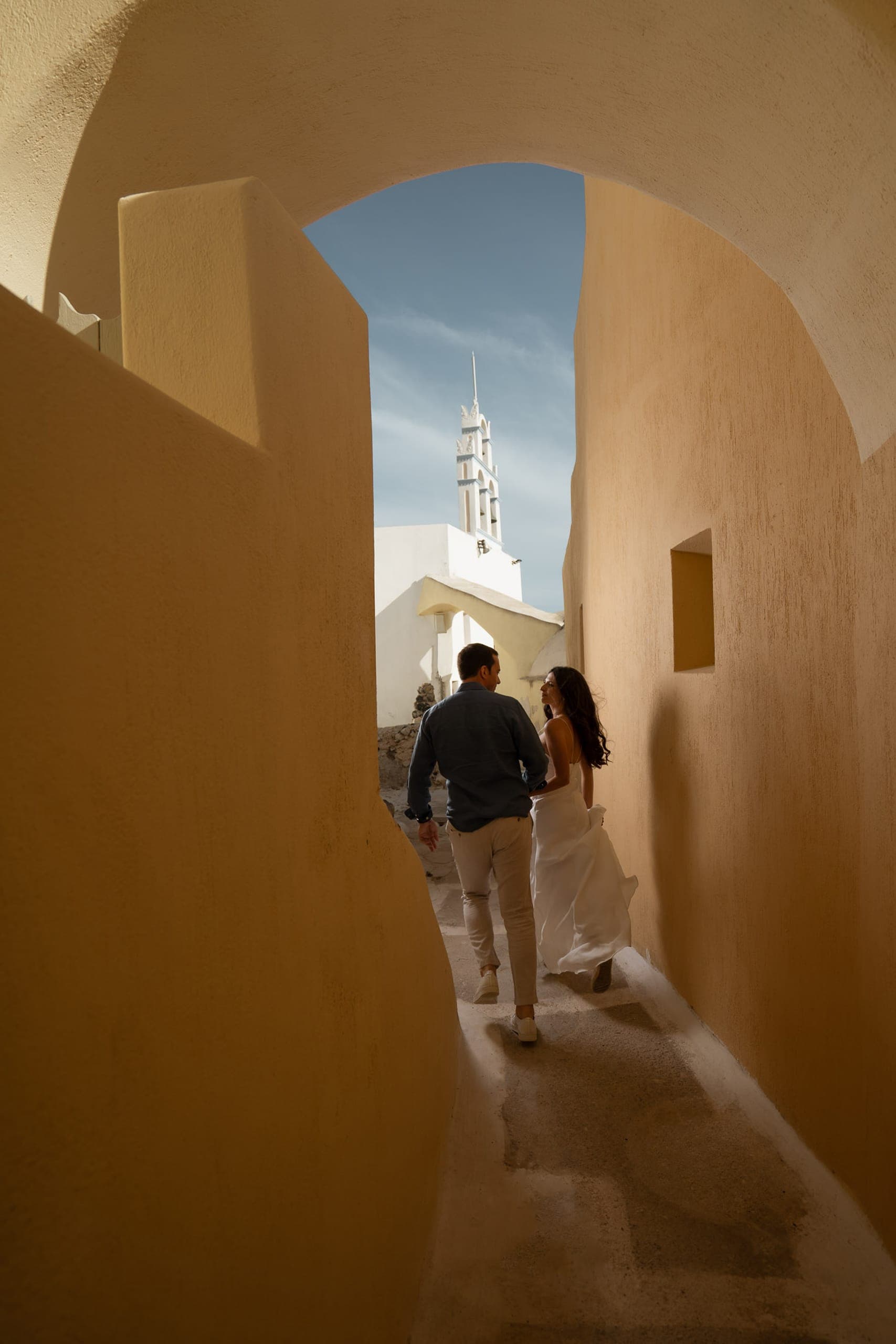 Couple running in the isles of Emporio village in Santorini.
