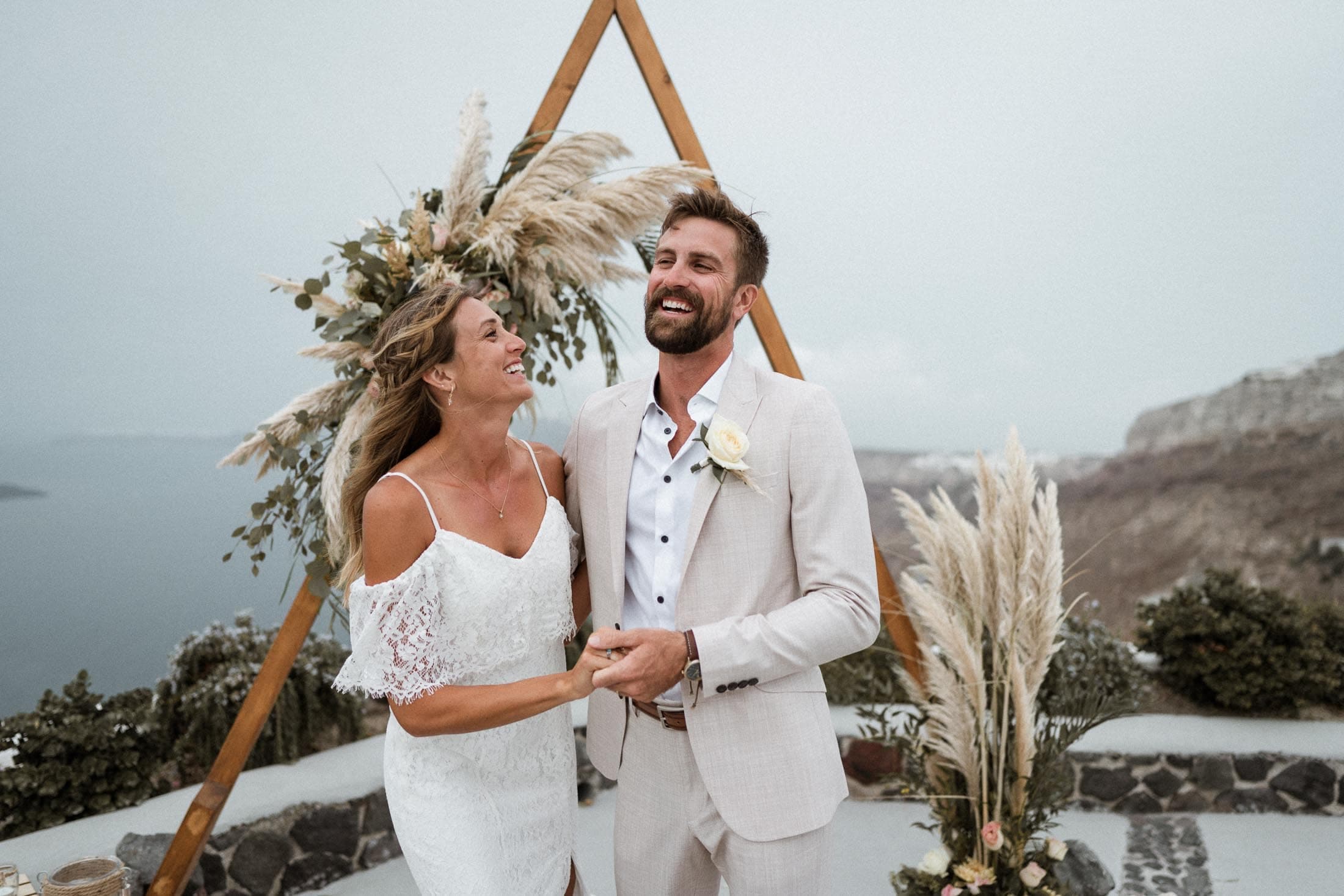 Wedding couple laughing during their exist after their elopement in Venetsanos winery in Santorini, Greece.