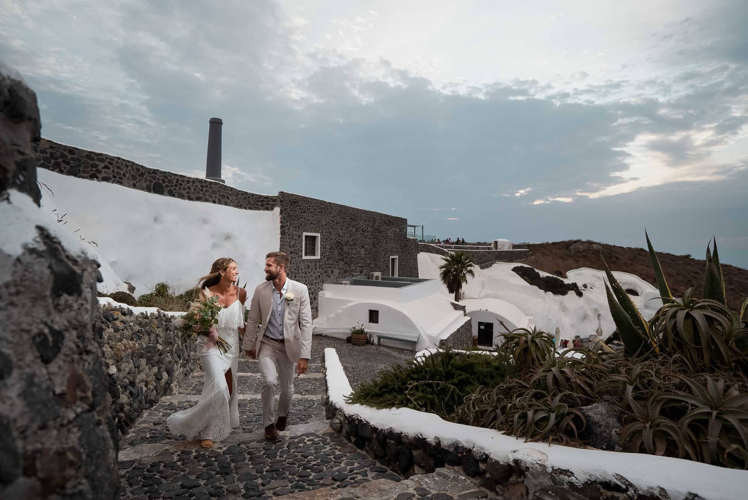 Wedding couple running at the stairwas of Venetsanos winery in Santorini, Greece.