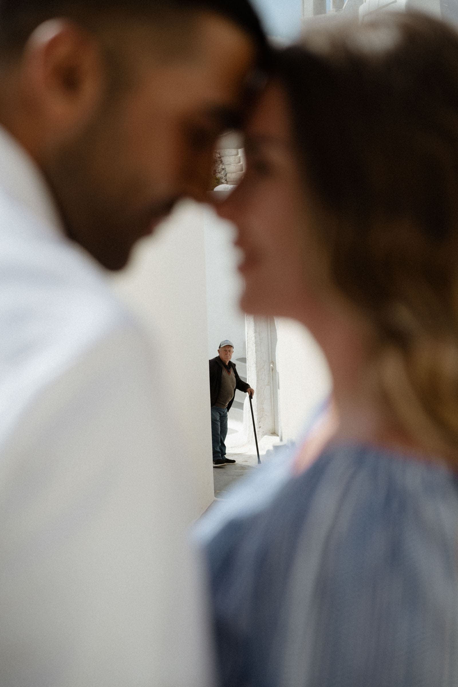 Couple about to kiss in Pyrgos village while an old may is walking by and looking at them.