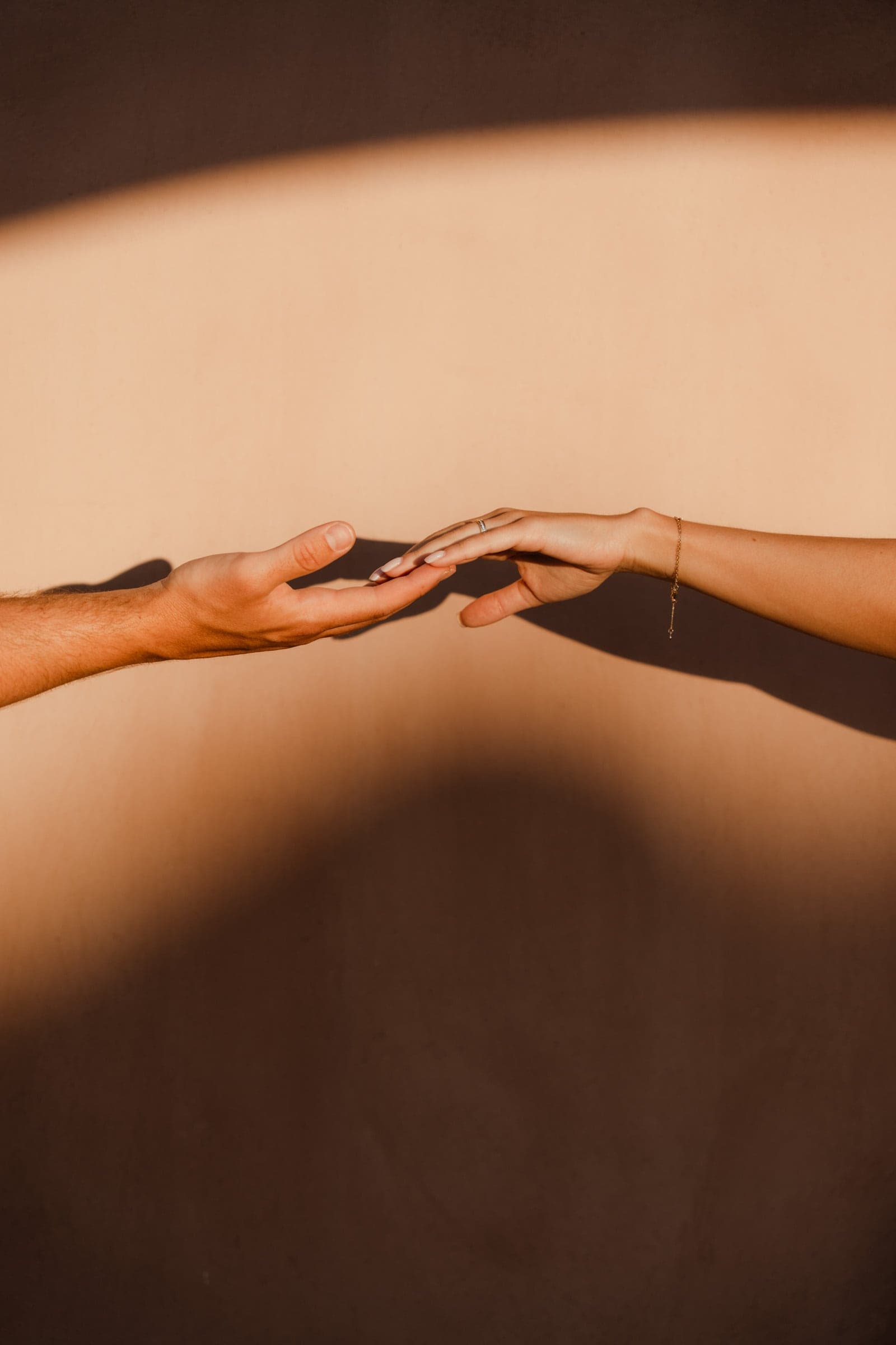 Hands touching against a red wall. Image taken right after their wedding proposal.