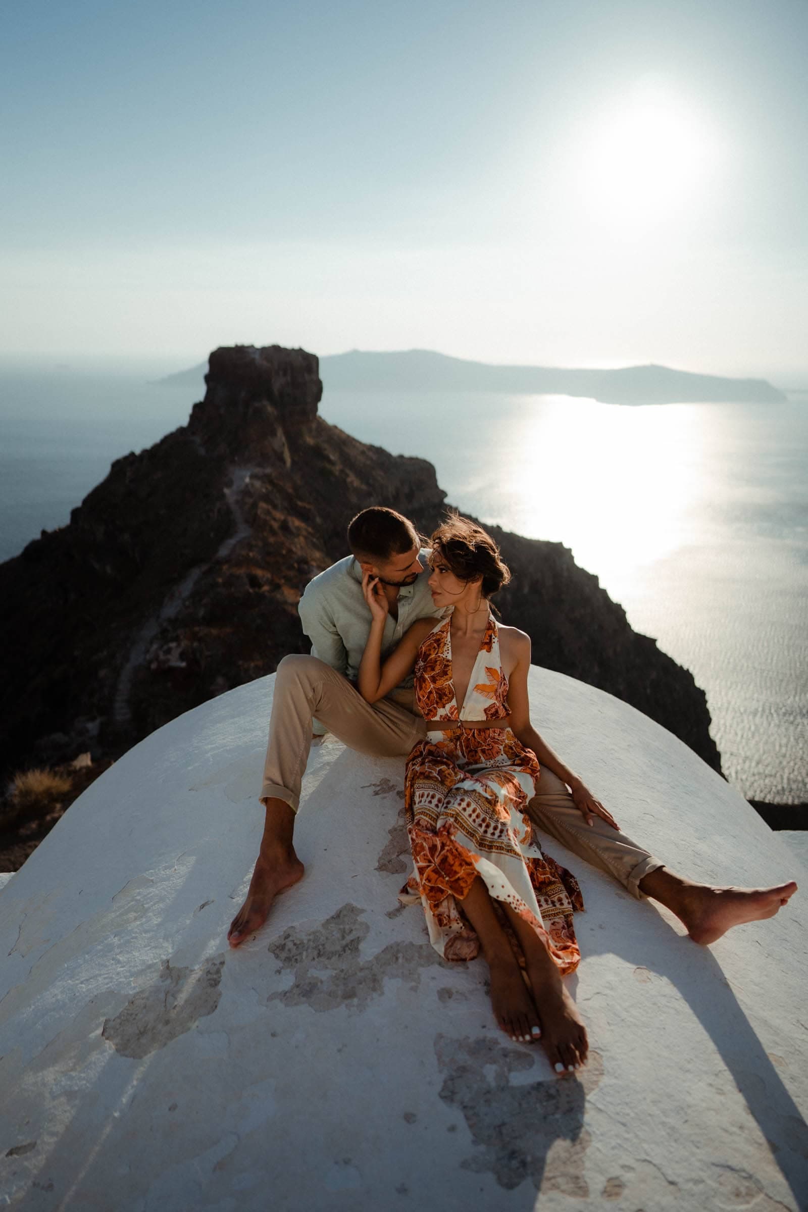 Couple laying down on the top of a chapel in Skaros rock during sunset.