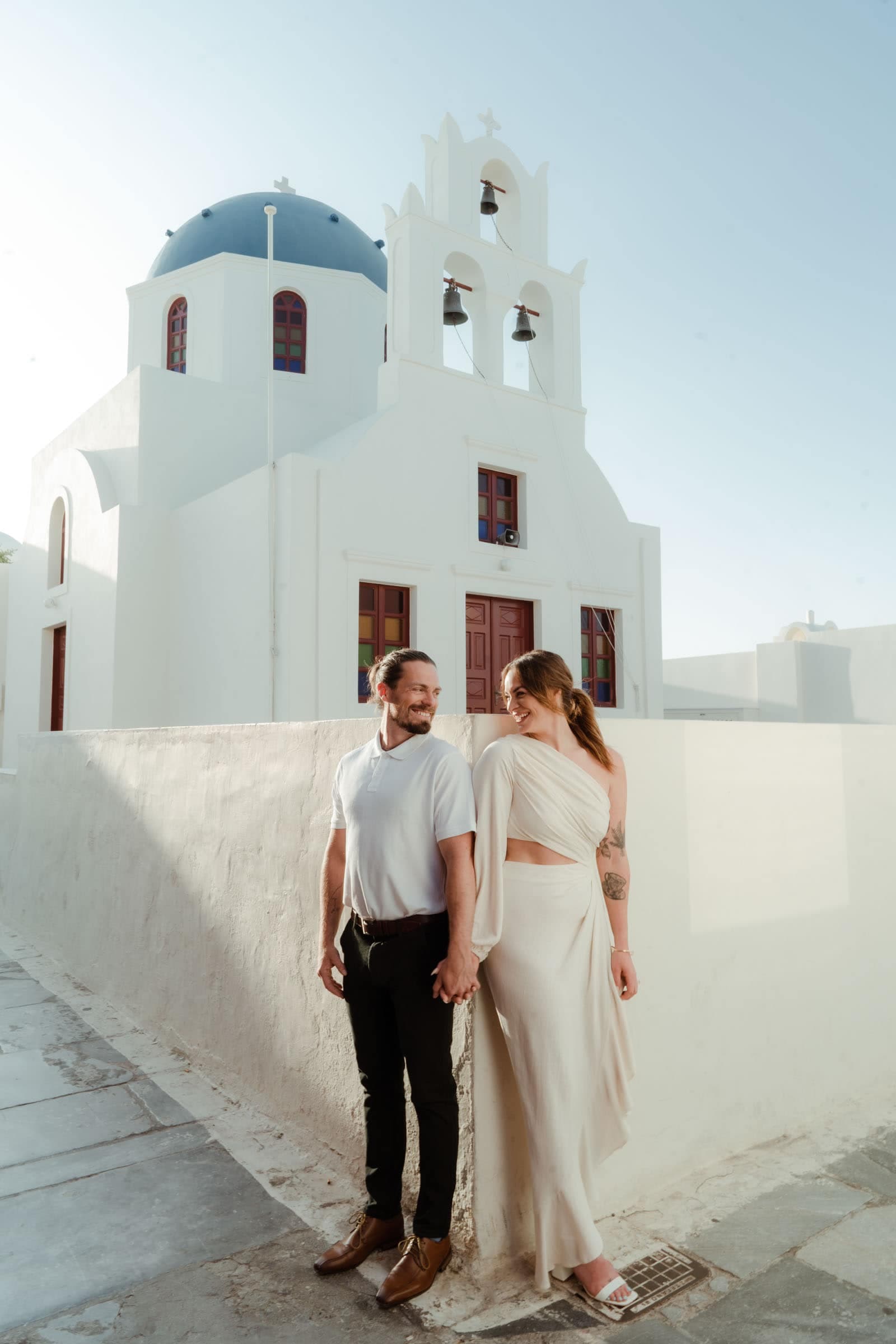 Couple posing in front of a blue dome in Oia.