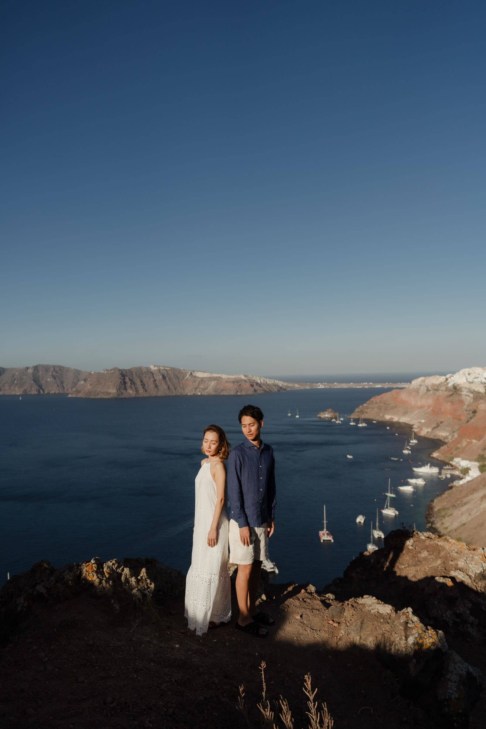 Japanesse couple posing at the top of a cliff in Oia, Santorini.