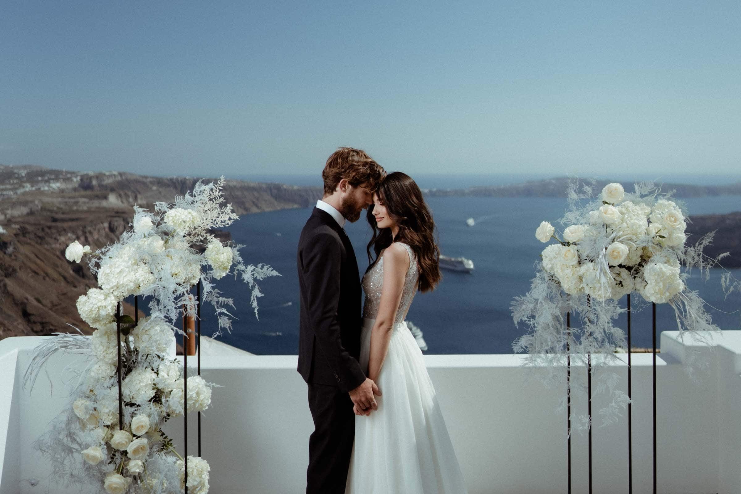 Couple posing right after their wedding ceremony in Santorini. They are stading at the terrace of Stella rocca a mare.